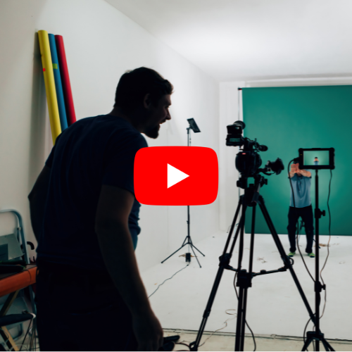 Video production setup with camera on a tripod and person in front of green screen.